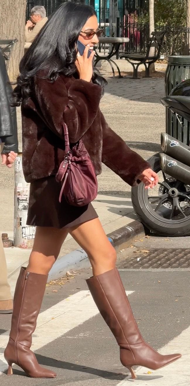 Brown faux fur jacket, mini skirt, and knee-high boots with a maroon drawstring bag.