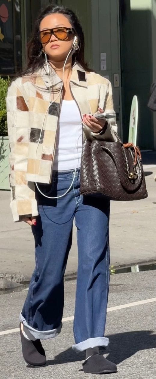Patchwork jacket, white top, blue wide-leg jeans, black mules, and woven brown bag.