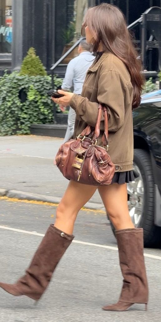 Brown utility jacket, black mini skirt, brown suede boots, and brown leather handbag.