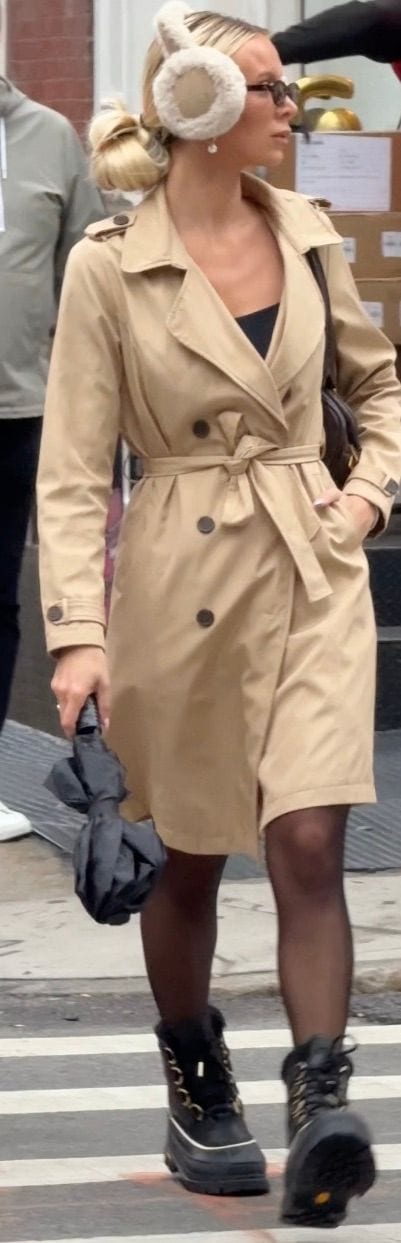 Beige trench coat with black tights and black snow boots, accessorized with fluffy earmuffs.
