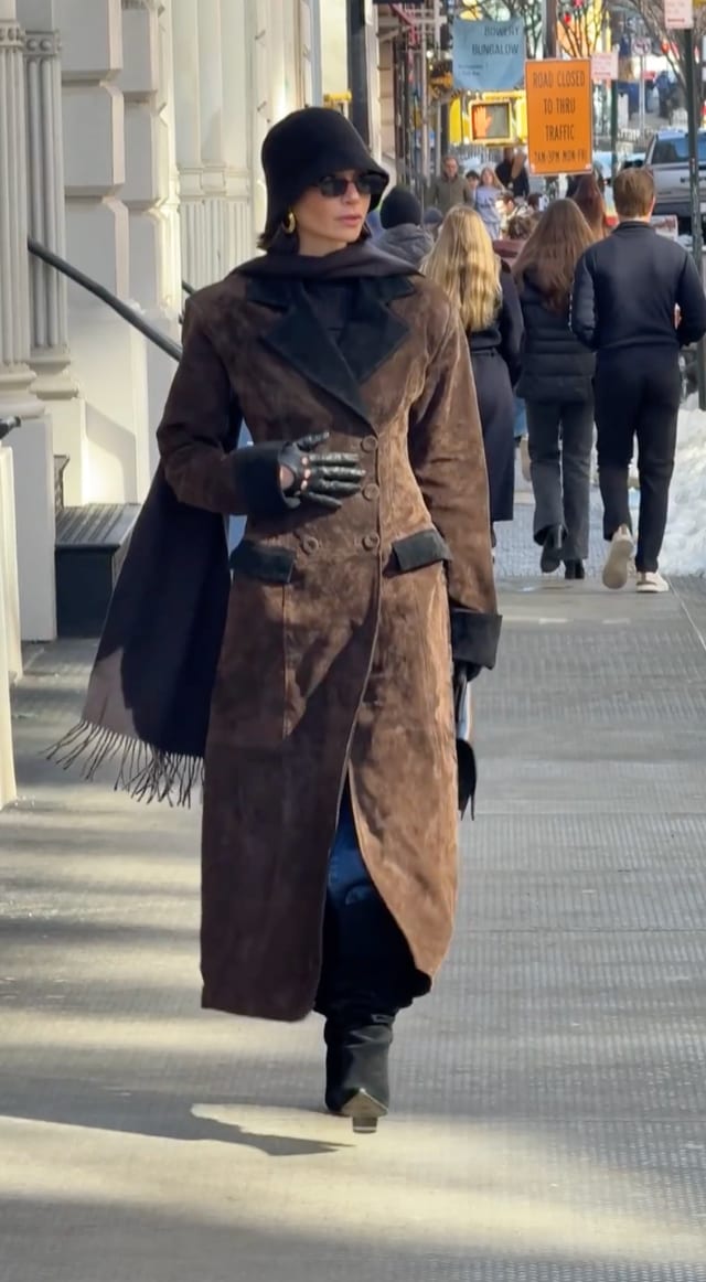 Brown suede trench coat with black trim, black bucket hat, scarf, and leather gloves.