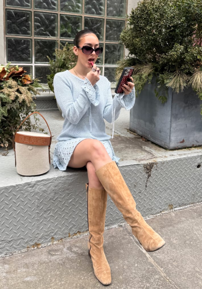 Light blue knit mini dress with bell sleeves, tan knee-high boots, and round sunglasses.