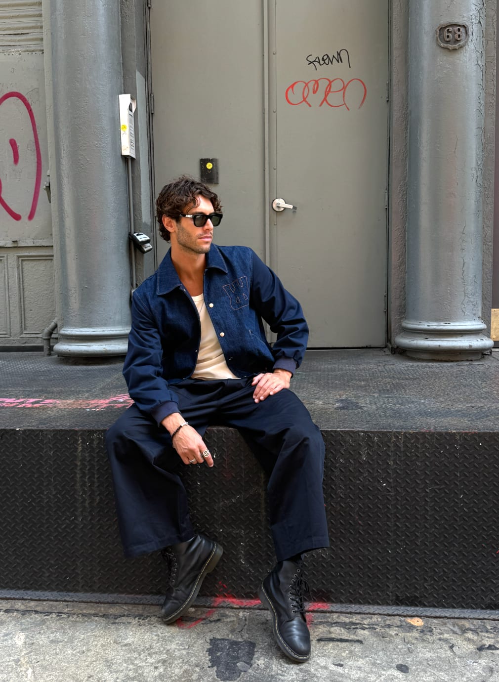 Dark blue denim jacket with black sleeves, black wide-leg pants, black boots, sunglasses.