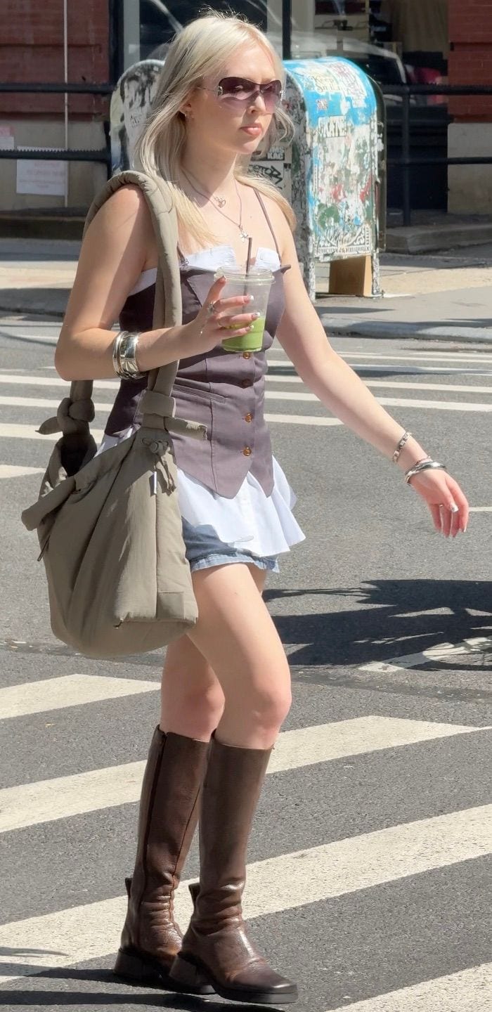 Brown strappy top over white blouse and denim shorts, brown knee-high boots, khaki bag.