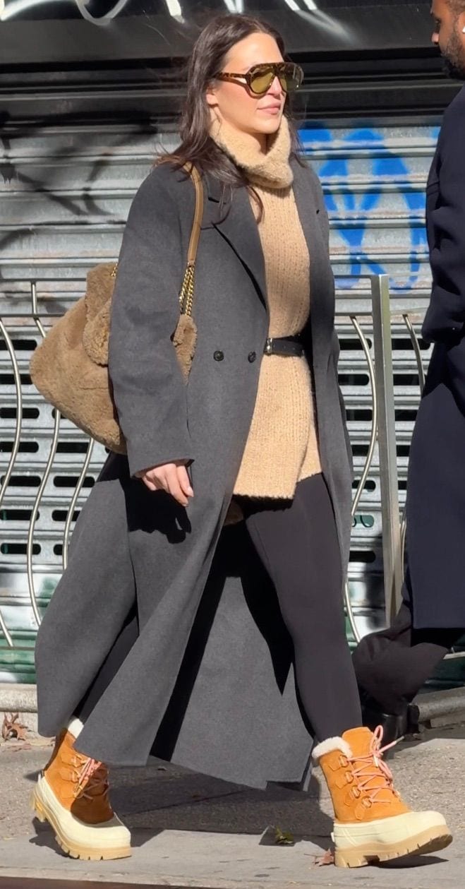 Gray long coat, beige turtleneck, black leggings, and brown snow boots.