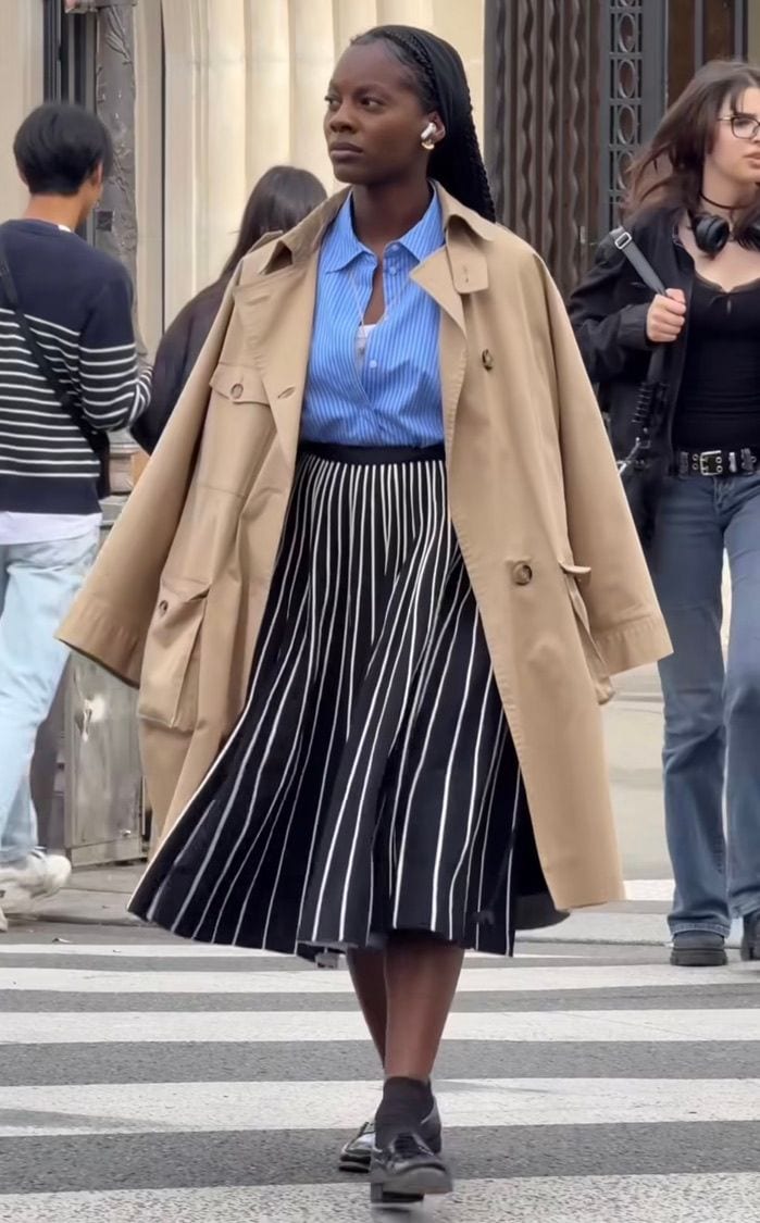 Tan trench coat over blue striped shirt and black/white striped skirt.