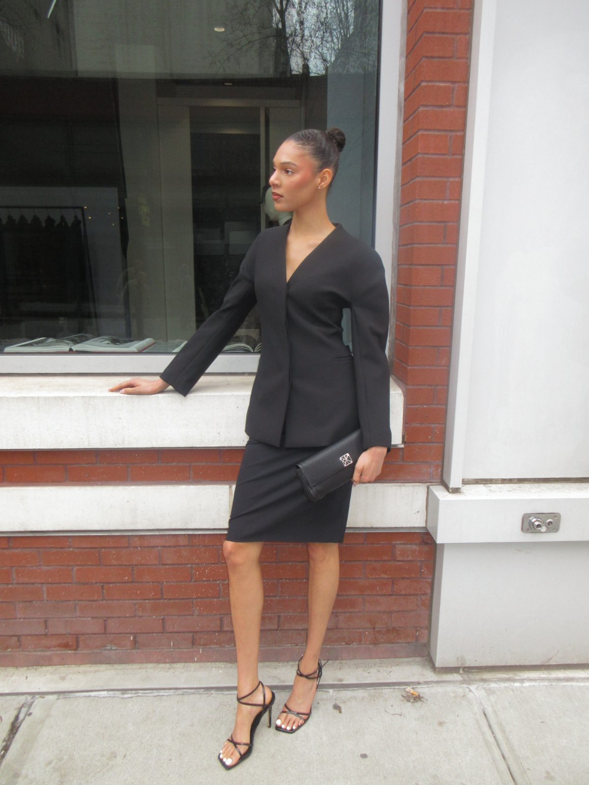 Black blazer, matching pencil skirt, black strappy heels, and black clutch.