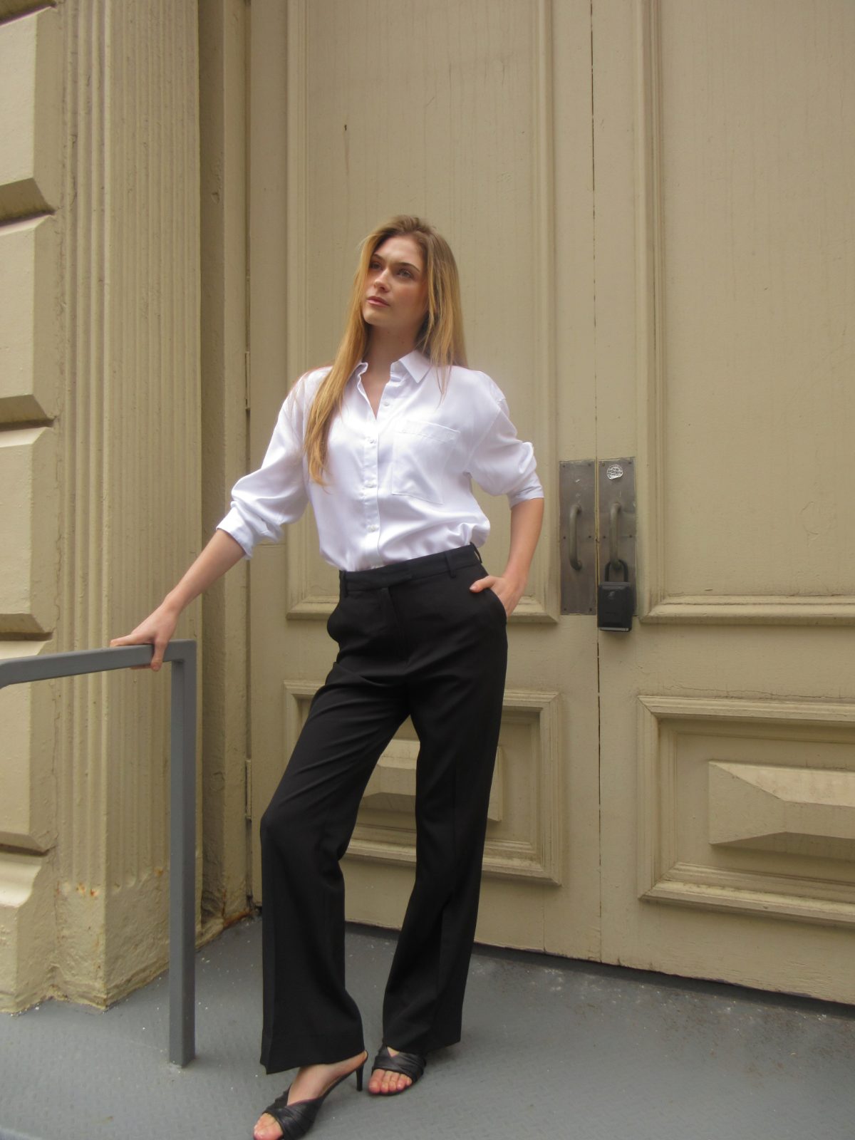 White silk button-up shirt with black trousers and black mules, business casual outfit.
