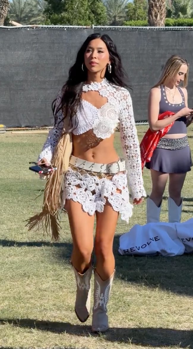 White crochet crop top and mini skirt, cowboy boots, and fringed bag.