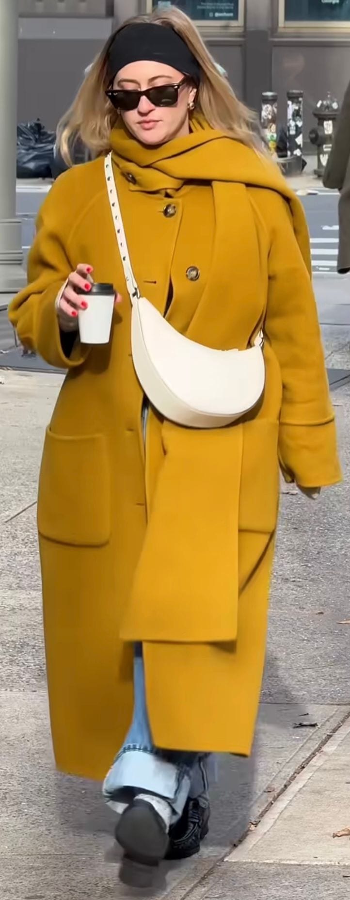 Mustard yellow wool coat with a white crescent bag, sunglasses, and black headband.