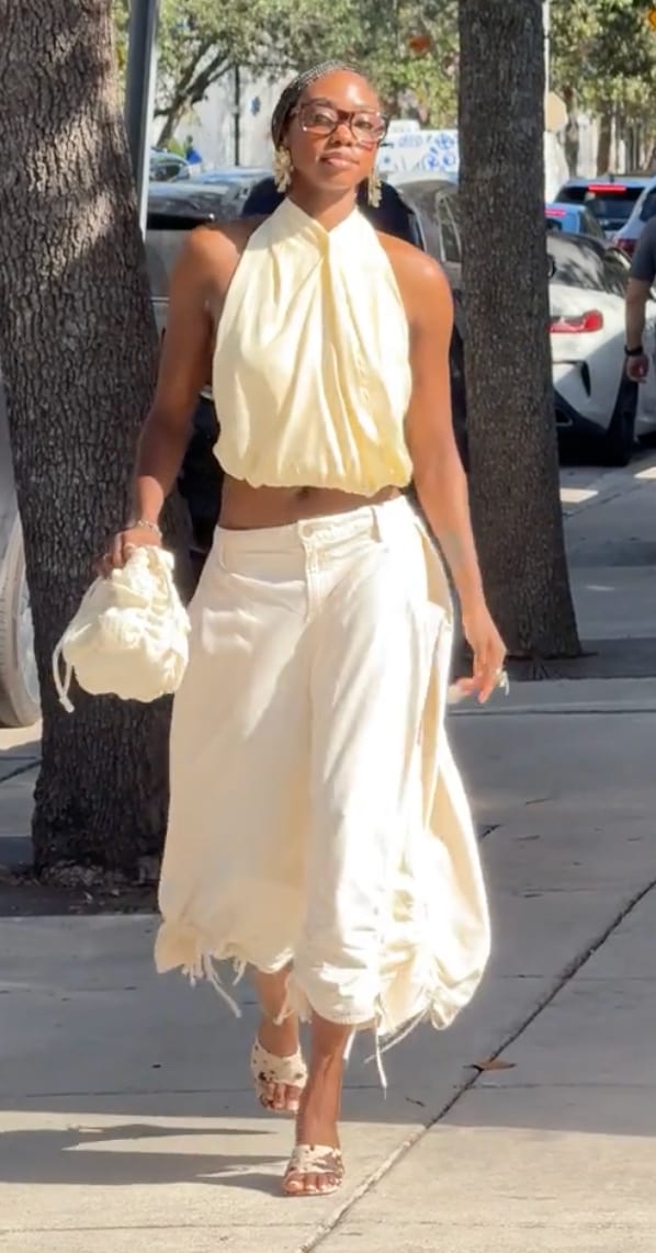 Light yellow halter crop top with cream baggy pants, matching bag, and patterned mules.