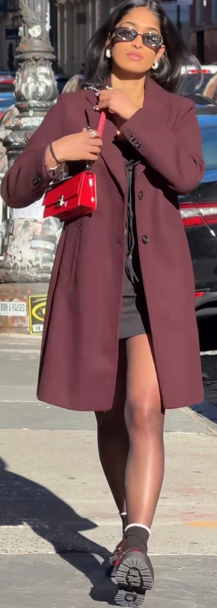 Maroon long coat, black mini dress, red patent bag, and chunky sole shoes.