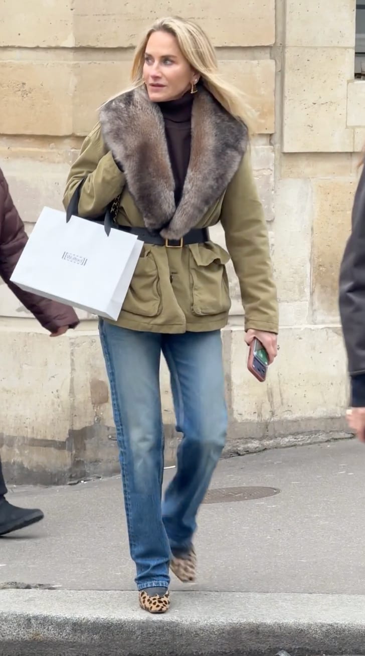 Olive green fur-collared jacket with a belt, blue jeans, and leopard print flats.